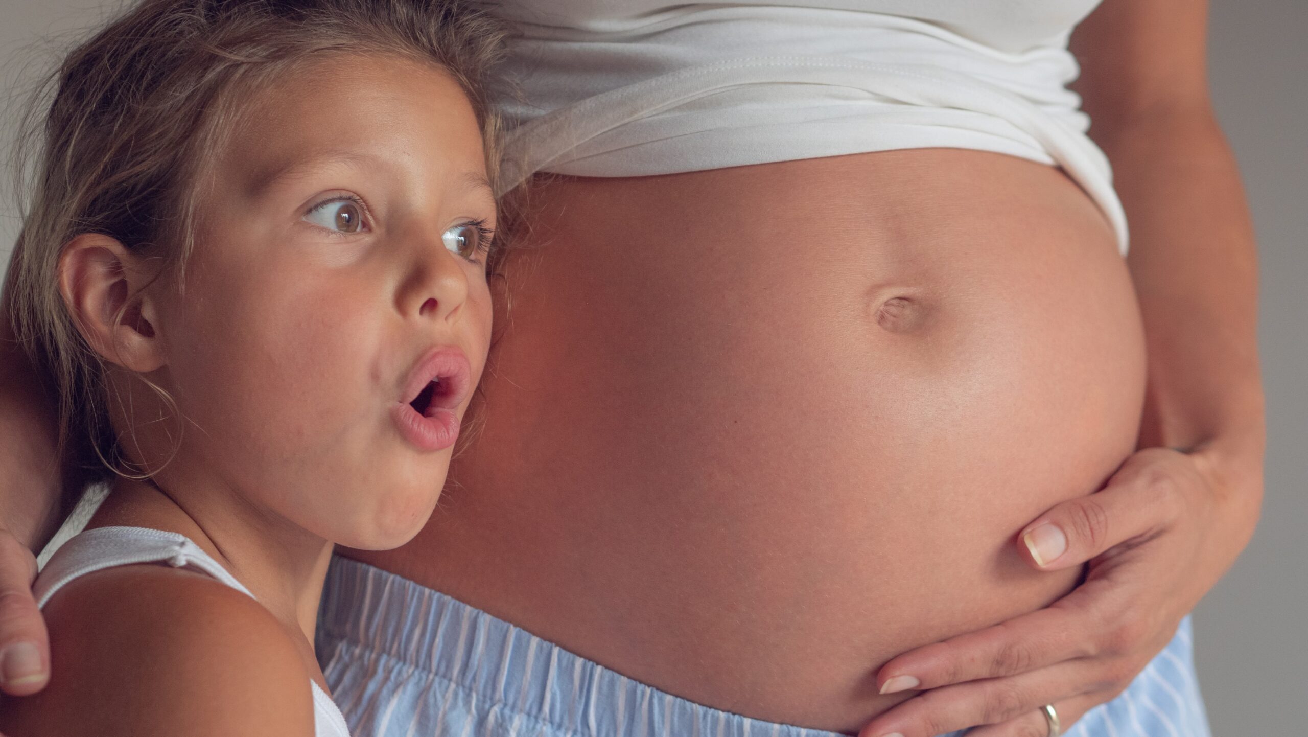 Malé dieťa sa dotýka tehotenského bruška svojej mamy